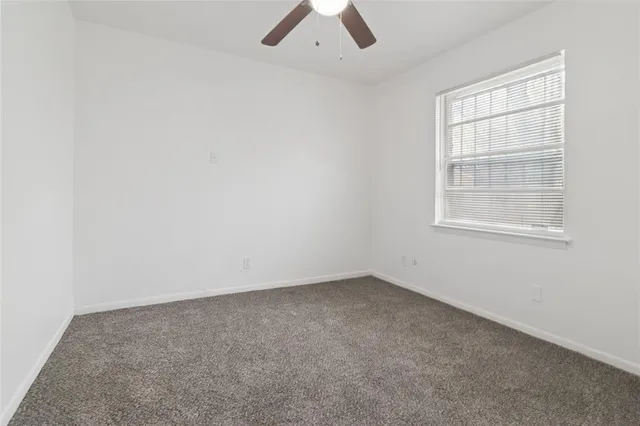 an empty room with ceiling fan and window