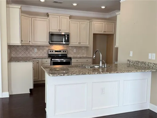 a kitchen with granite countertop white cabinets and stainless steel appliances