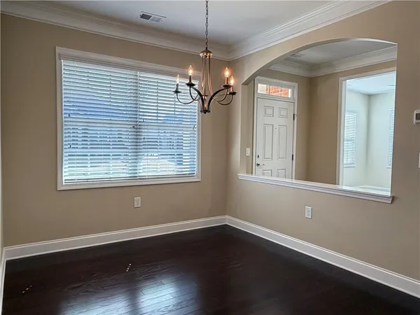 a view of a room with wooden floor a chandelier and windows