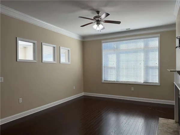 a view of an empty room with wooden floor and a window
