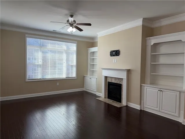 a view of an empty room with wooden floor fireplace and a window