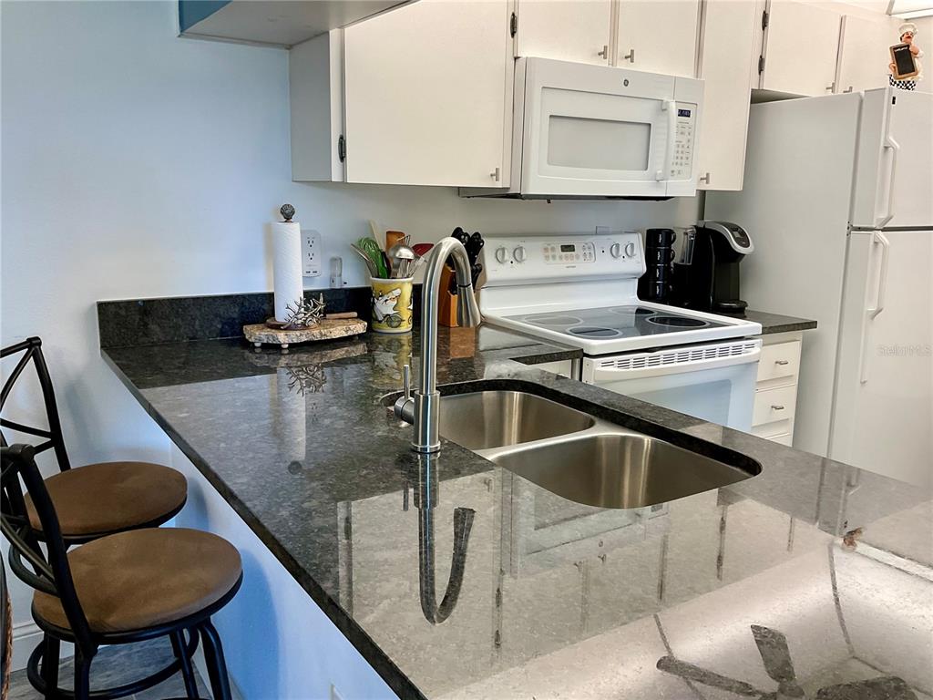 3213 South Beneva Road, Unit 204 Sarasota, FL 34232 - Photo 8 of 18 a kitchen with stainless steel appliances granite countertop a sink refrigerator and cabinets