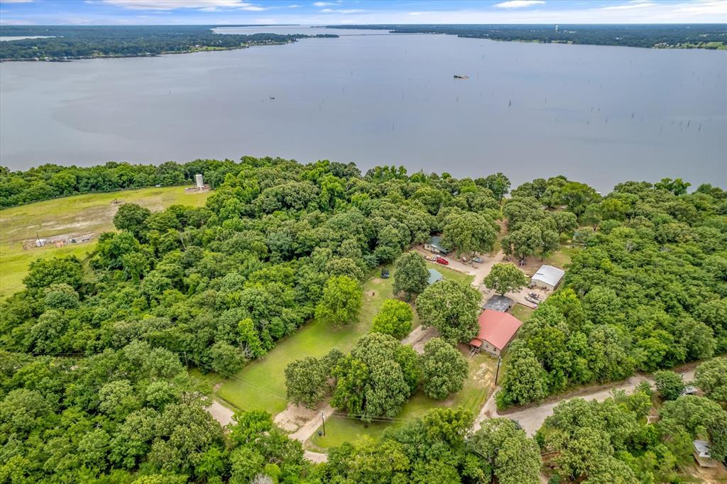 Aerial overview of property's location featuring a nearby body of water and a heavily wooded area