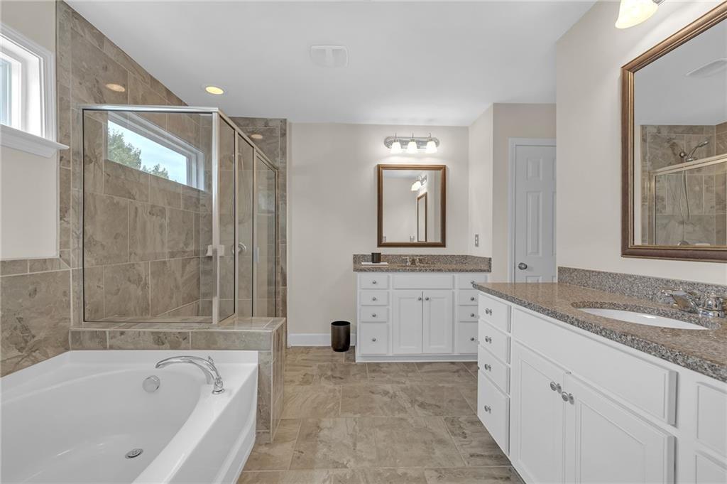6513 Bennington Bluff Court, Unit 2 Mableton, GA 30126 - Photo 21 of 41 a bathroom with a granite countertop sink a mirror a bathtub and next to a window