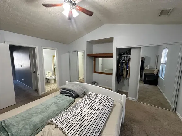 a bed sitting in a bedroom next to a window and a chandelier