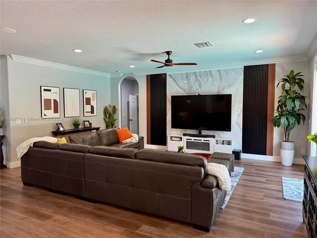 a living room with furniture flat screen tv and a large window
