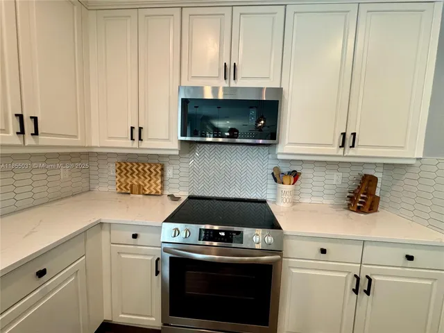 a kitchen with granite countertop a table chairs stove and refrigerator