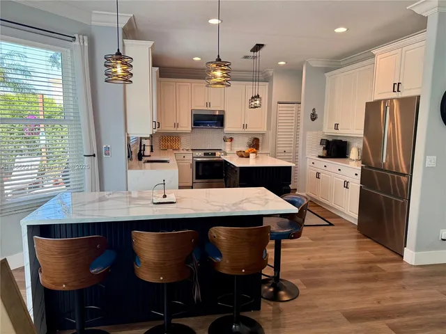 a kitchen with refrigerator a microwave a stove a sink dishwasher and a refrigerator with wooden floor