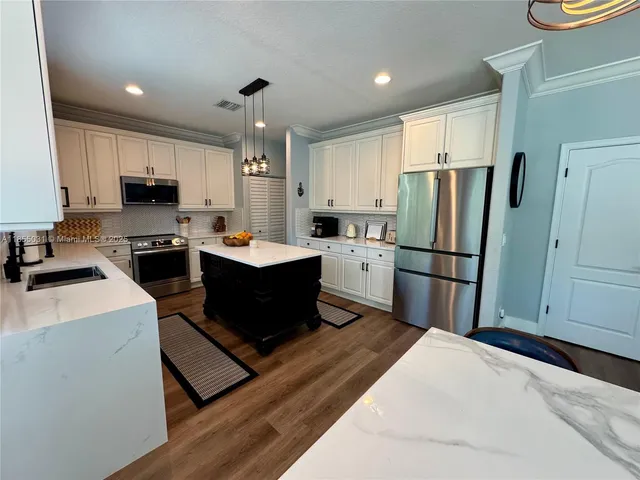 a kitchen with a stove a sink a refrigerator and cabinets