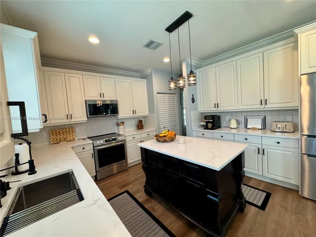 a kitchen with a sink a kitchen island a stove a dining table and chairs