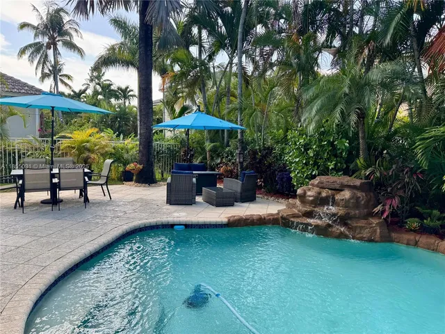 a view of a patio with couches table and chairs potted plants and palm tree