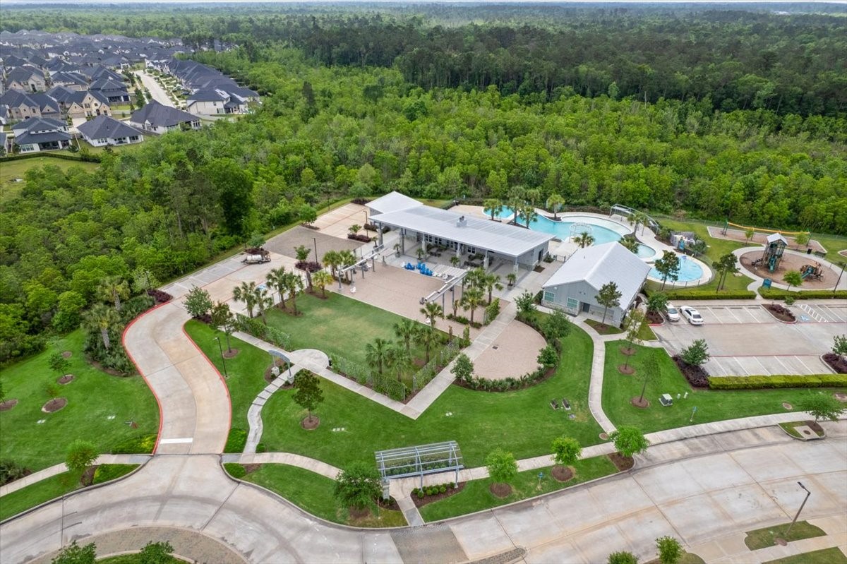 17814 Tree Of Heaven Conroe, TX 77385 - Photo 30 of 48 South Village – Resort-style amenity center surrounded by lush greenery, featuring a recreation center with pavilion and event lawn with retractable solar shade panels. Enjoy a resort-style pool with multi-use deck, toddler and adult areas, sun shelf, cabanas, and a splash pad.
