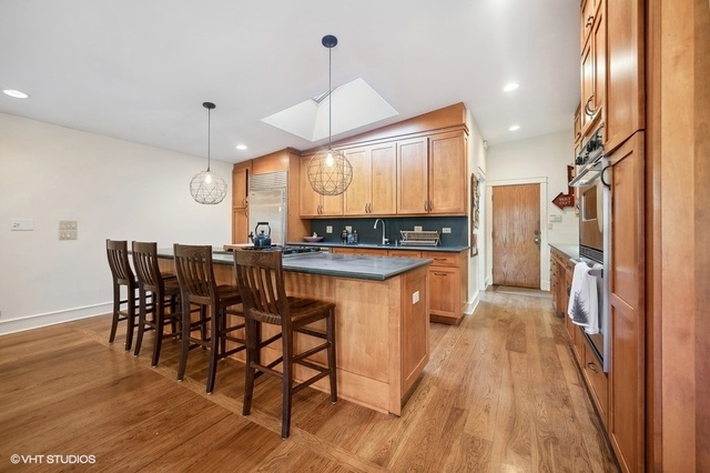 687 Birch Road Glencoe, IL 60022 - Photo 15 of 38 a kitchen with stainless steel appliances kitchen island granite countertop a table chairs stove and a wooden floor
