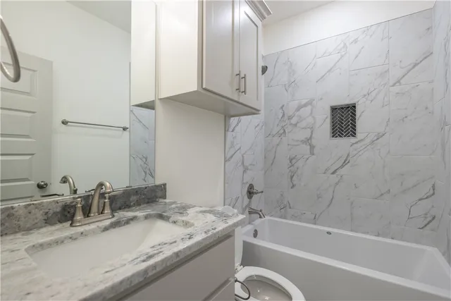 a bathroom with a granite countertop sink and a bathtub