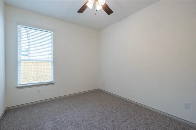 an empty room with a window and a ceiling fan