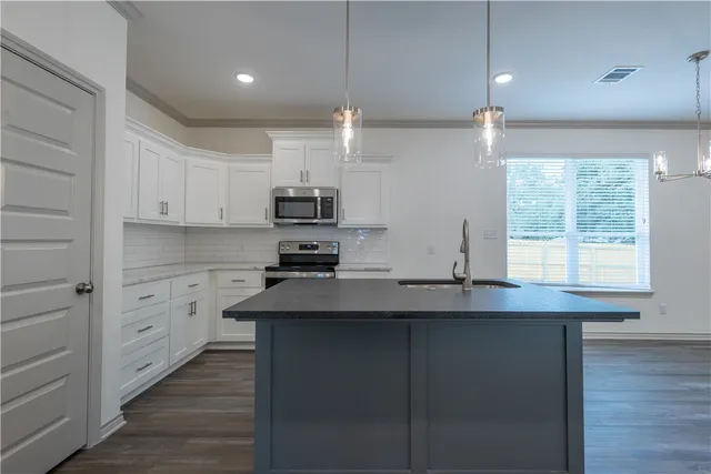 a kitchen with kitchen island granite countertop a sink cabinets and wooden floor