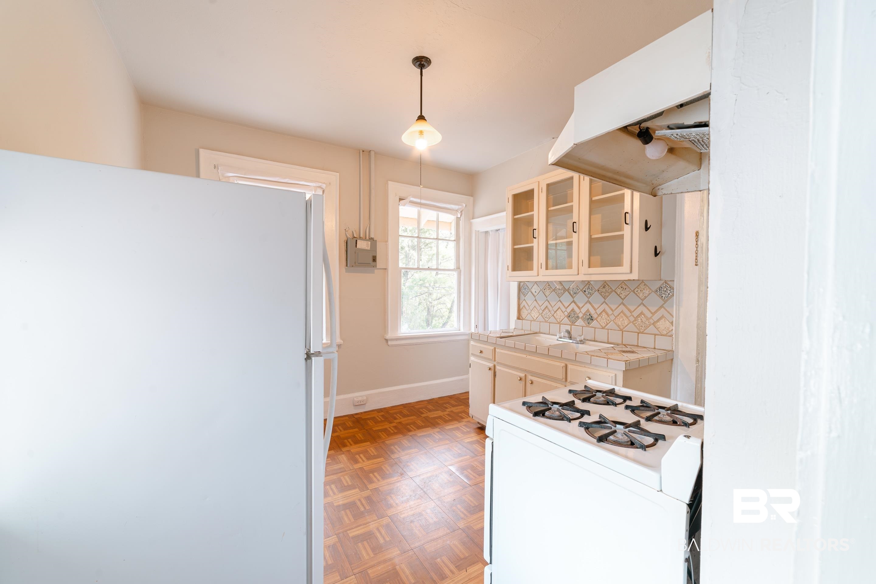 312 1st Street Mobile, AL 36611 - Photo 8 of 29 Kitchen with decorative backsplash, tile countertops, light parquet flooring, decorative light fixtures, and white appliances
