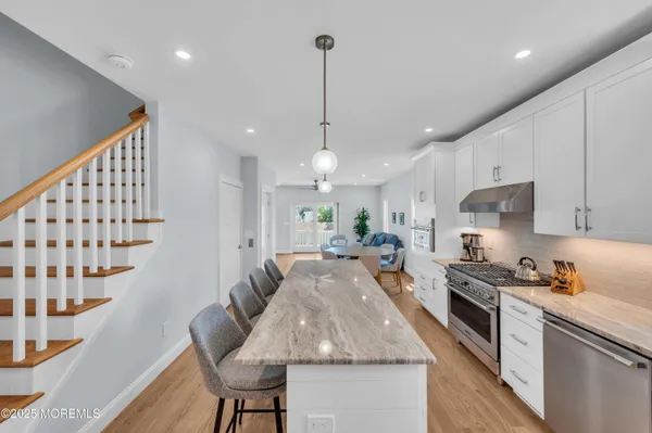 a kitchen with granite countertop kitchen island stainless steel appliances a stove a sink a refrigerator a center island a dining table and chairs