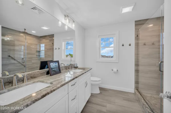 a bathroom with double vanity sinks a toilet a mirror and shower