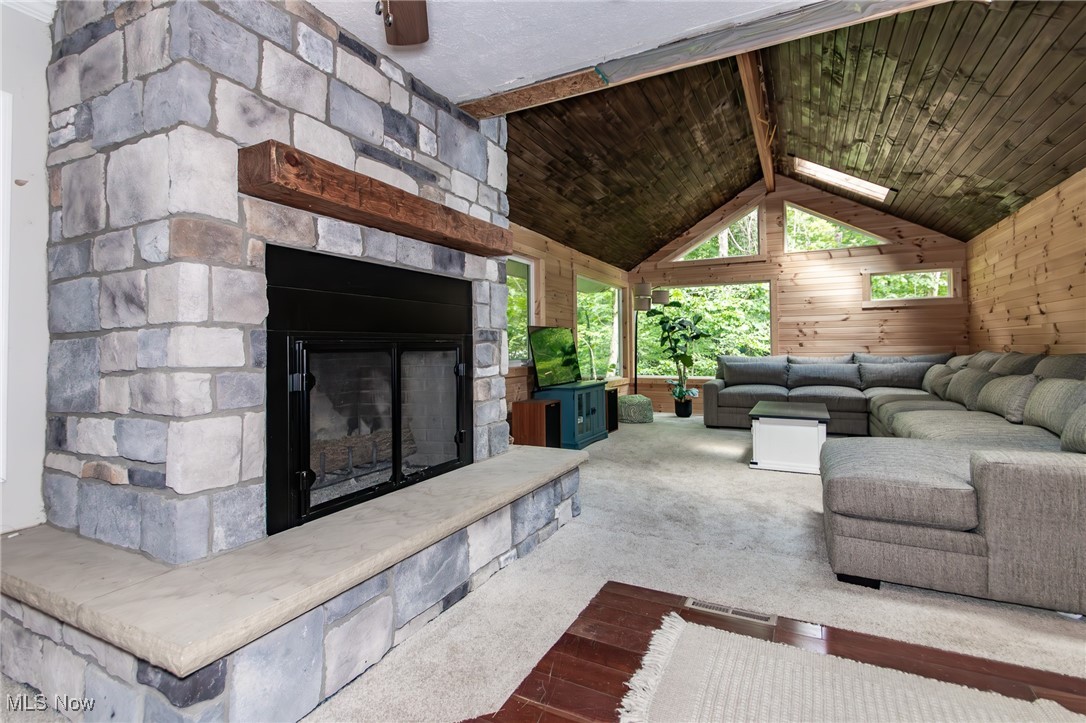 9723 Thwing Road Chardon, OH 44024 - Photo 8 of 42 Carpeted living area with wood walls, vaulted ceiling, an outdoor stone fireplace, and wooden ceiling