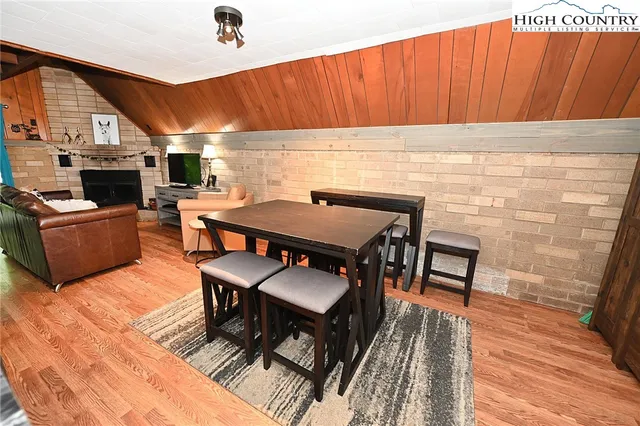 a view of a dining room with furniture a fireplace and wooden floor