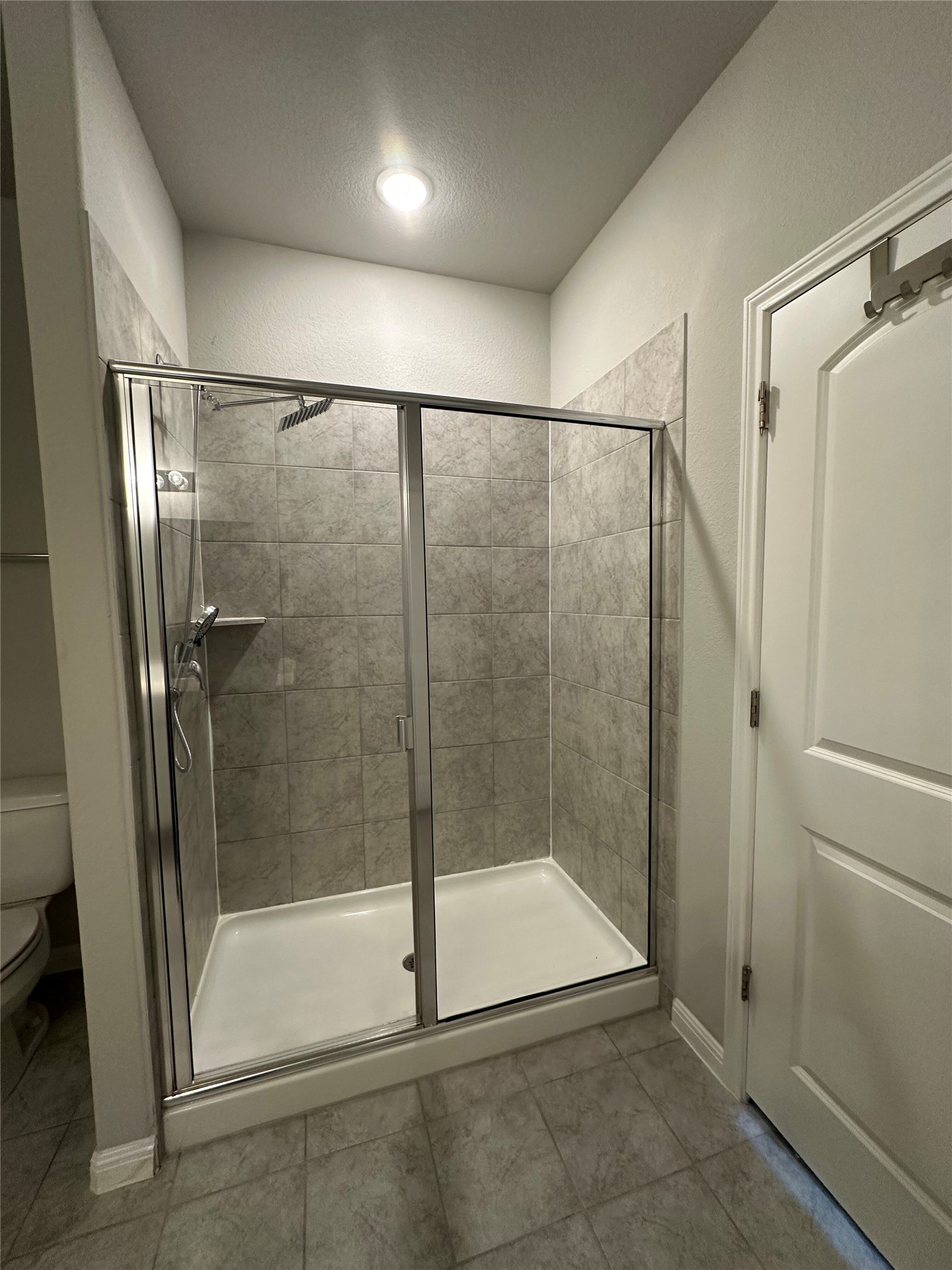 13000 Titanium Street Austin, TX 78754 - Photo 6 of 15 Walk-in shower with clear glass enclosure and chrome hardware, featuring large format rectangular wall tiles and a built-in shower niche