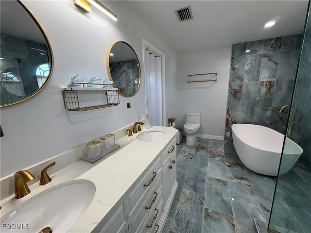 a bathroom with a granite countertop sink mirror and toilet