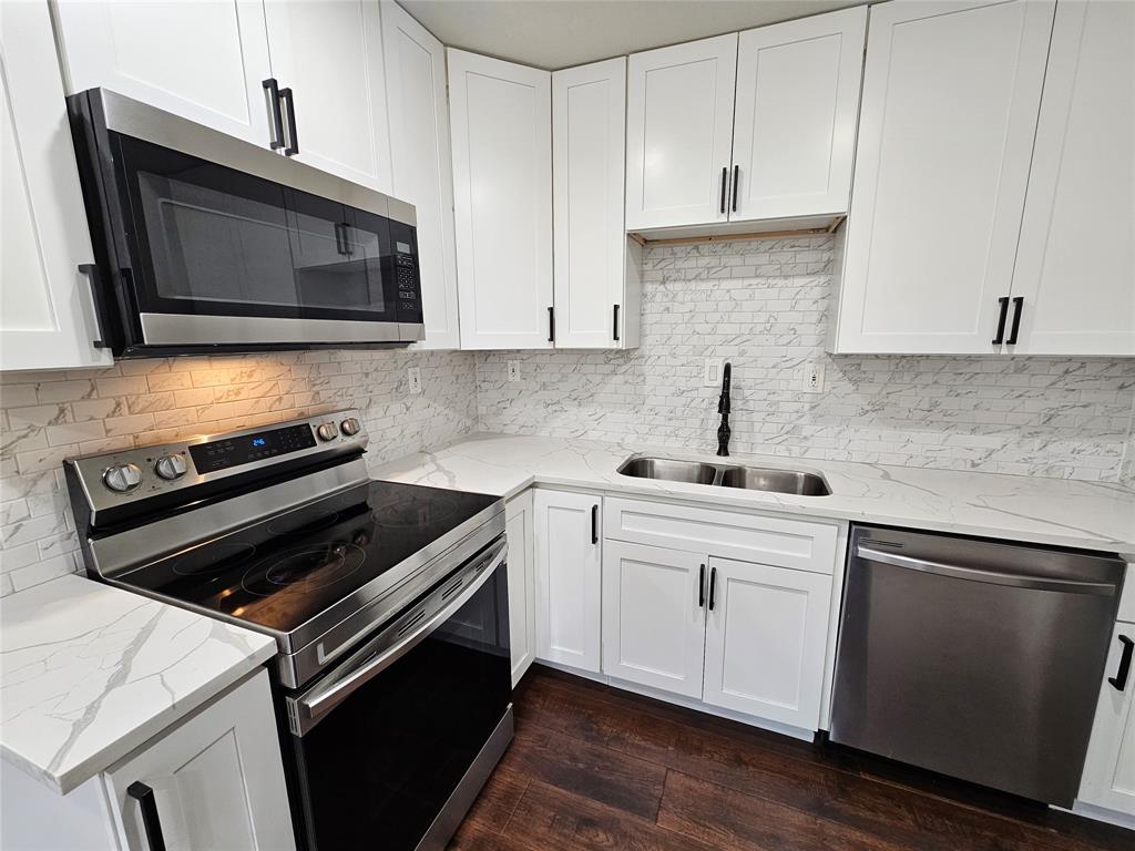 211 North Hampton Road Dallas, TX 75208 - Photo 10 of 22 Kitchen featuring white shaker cabinetry, stainless steel appliances, a dual basin sink with a matte black faucet, and wood-finish flooring