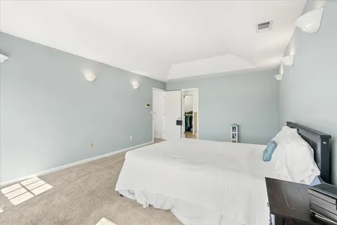 a spacious bedroom with a bed chandelier and a window
