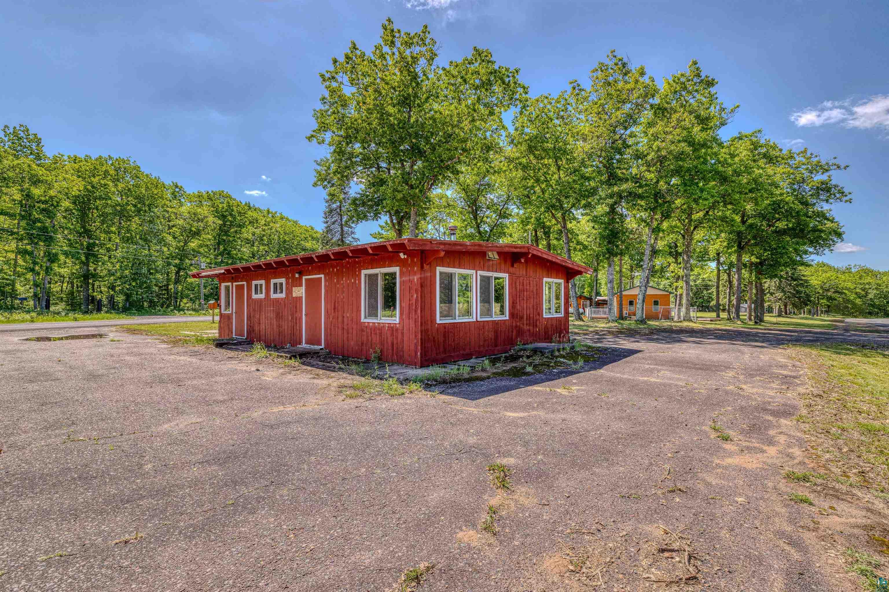 66075 Rooster Road Iron River, WI 54847 - Photo 49 of 52 Red-sided structure with multiple windows and doors, set on an asphalt lot