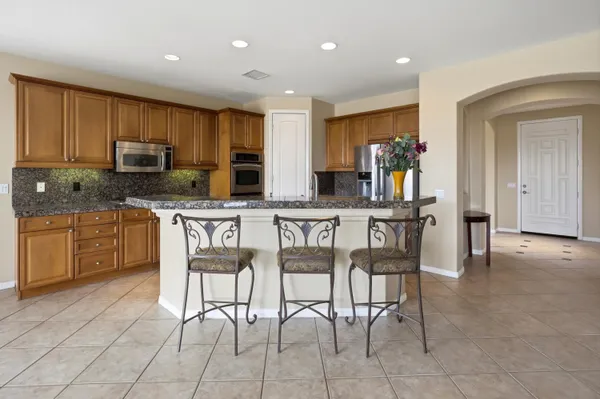 a kitchen with stainless steel appliances kitchen island granite countertop a stove a sink a microwave a dining table and chairs