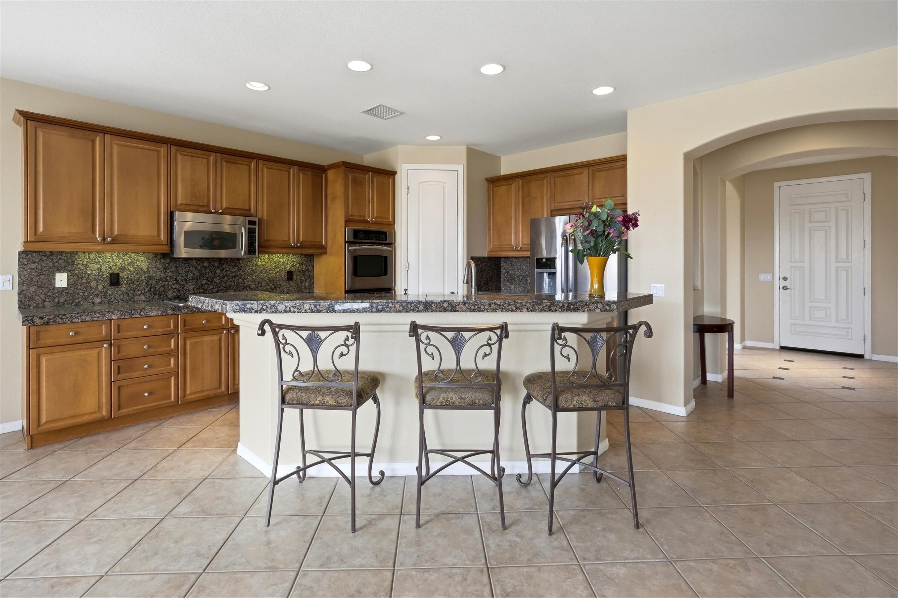 232 Via Firenza Rancho Mirage, CA 92270 - Photo 12 of 43 a kitchen with stainless steel appliances kitchen island granite countertop a stove a sink a microwave a dining table and chairs