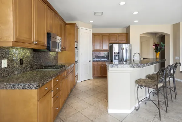 a kitchen with kitchen island granite countertop a stove top oven a sink a dining table and chairs