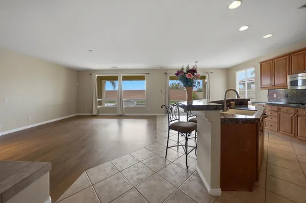 a living room with couches and kitchen view with wooden floor