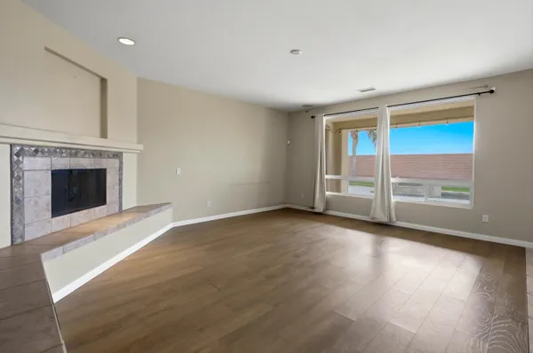an empty room with wooden floor fireplace and windows