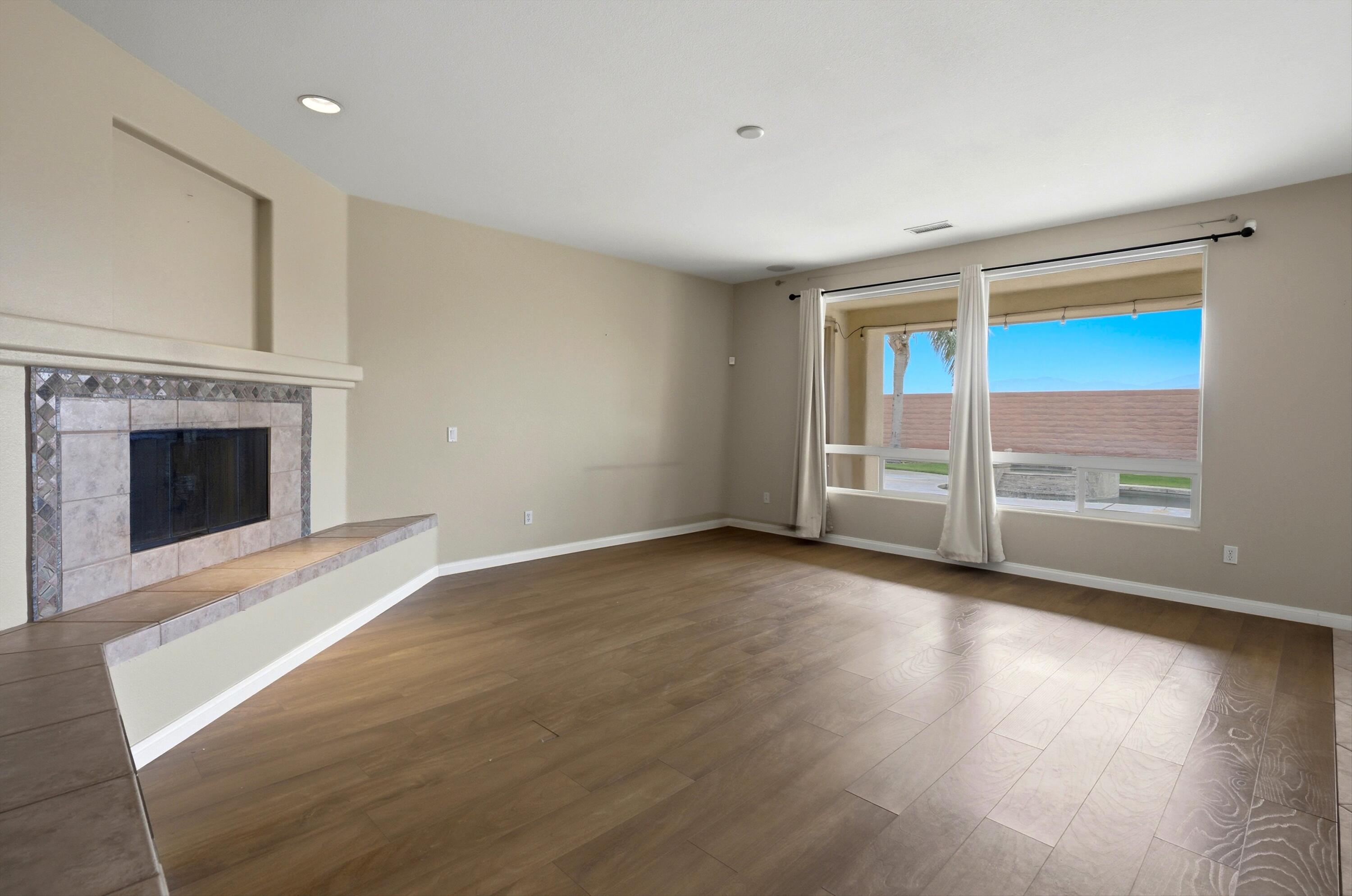 232 Via Firenza Rancho Mirage, CA 92270 - Photo 8 of 43 an empty room with wooden floor fireplace and windows