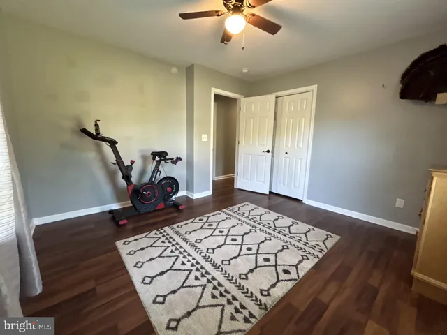 a view of a bedroom with wooden floor and ceiling fan
