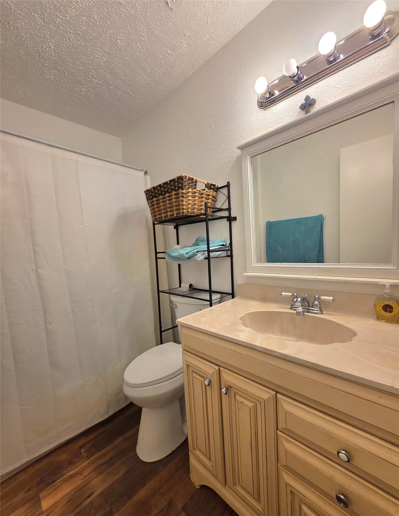 15208 Spring Hill Lane, Unit A Pflugerville, TX 78660 - Photo 13 of 16 Bathroom featuring a light-colored vanity with an integrated sink and chrome fixtures, framed mirror, and wood-finish flooring