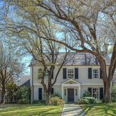 a view of a white house with a large tree