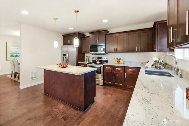 a kitchen with stainless steel appliances granite countertop wooden cabinets a sink a stove a refrigerator and a oven