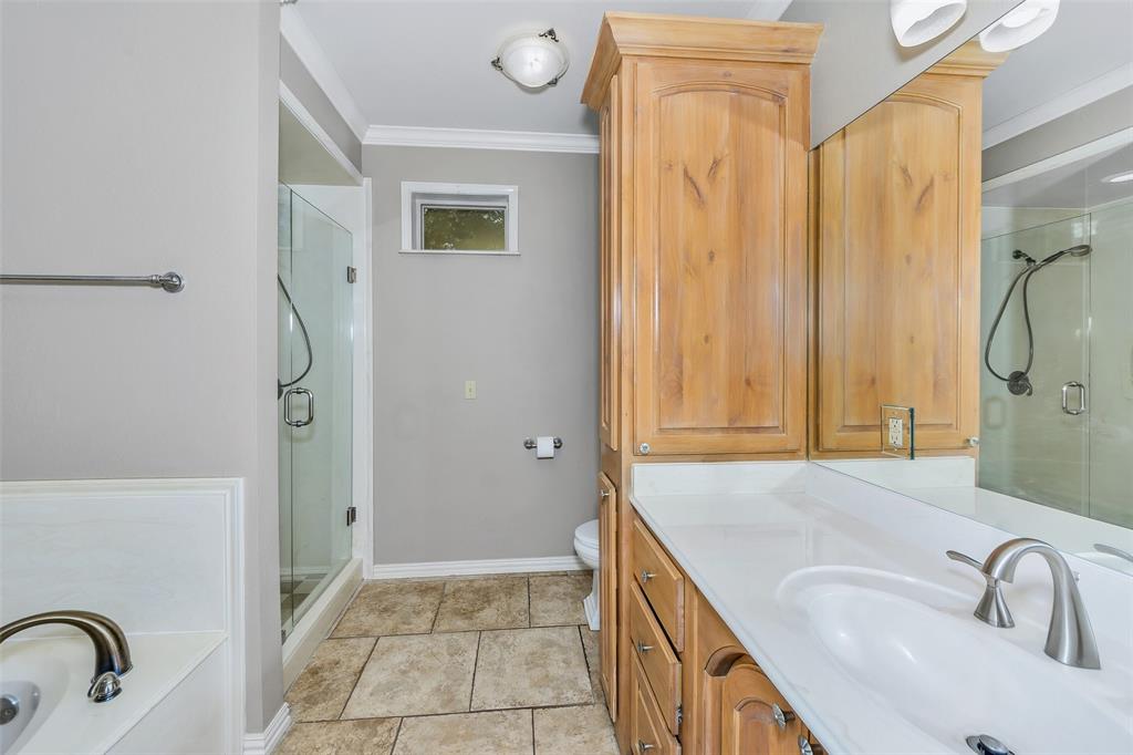 566 Selma Park Road Bowie, TX 76230 - Photo 17 of 40 Bathroom featuring a glass-enclosed shower, built-in wooden cabinetry, a white countertop vanity with an integrated sink, and large format floor tiling