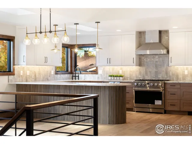 a kitchen with stainless steel appliances granite countertop a stove a sink dishwasher a refrigerator and a oven with wooden floors