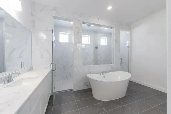 a bathroom with a white tub a sink and mirror