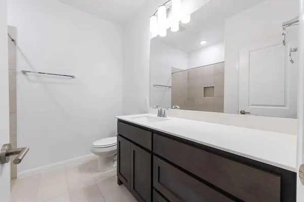 a bathroom with a sink a toilet a mirror and shower