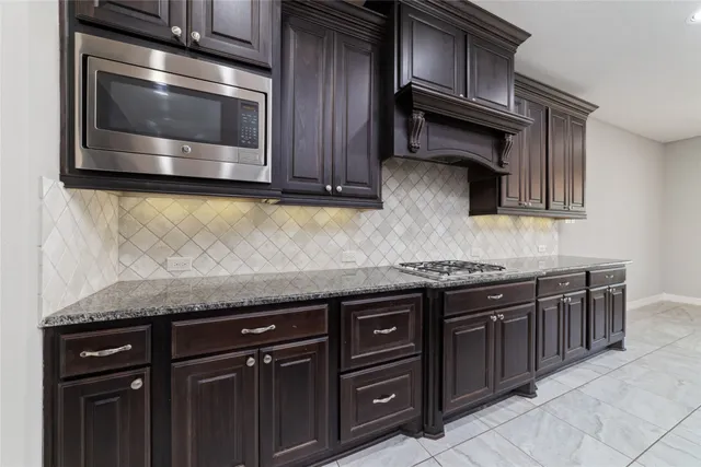 a kitchen with granite countertop a stove top oven microwave and cabinets