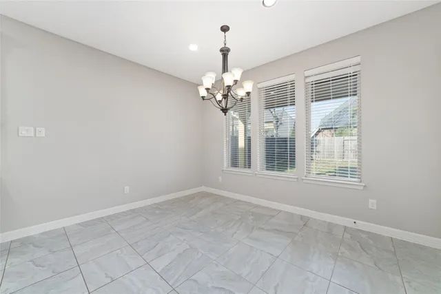 a view of an empty room with a chandelier fan and window