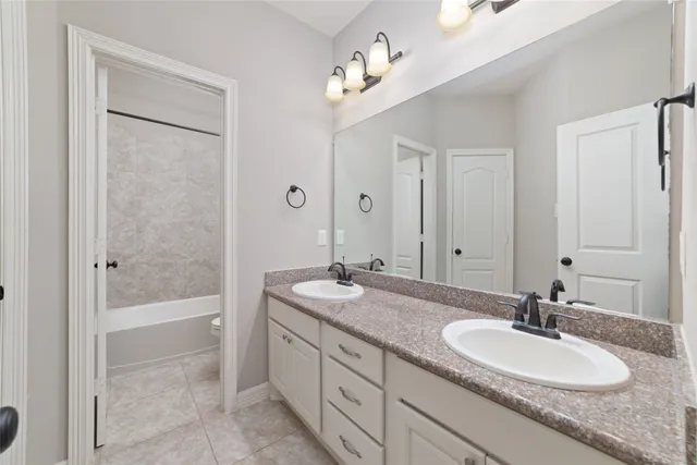 a bathroom with a granite countertop sink a mirror and a bathtub