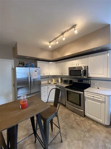 a kitchen with stainless steel appliances a table chairs and a refrigerator