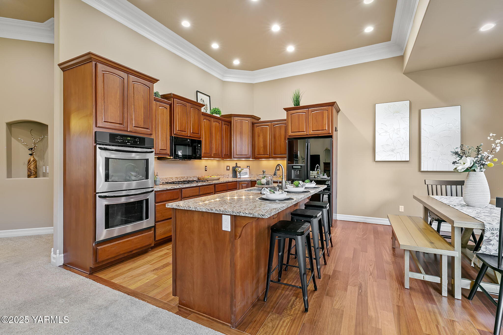 609 North 74th Avenue Yakima, WA 98908 - Photo 14 of 34 a kitchen with stainless steel appliances granite countertop a stove a refrigerator a kitchen island a stove a sink a dining table and chairs with wooden floor