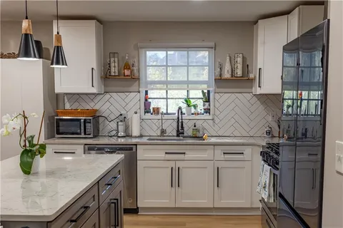 a kitchen with kitchen island granite countertop a sink a counter space appliances and cabinets